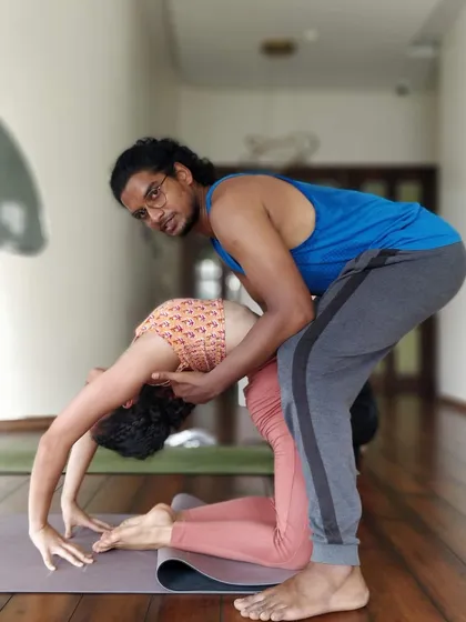 A teacher offers gentle guidance in Ustrasana, the camel pose. This support helps the student to lift the chest and lengthen the spine, preventing compression in the lower back and encouraging a more open, expansive backbend.