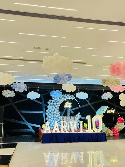 A wide view of a large hall decorated with a "sky and clouds" theme, including multiple balloon clouds and a stage setup.