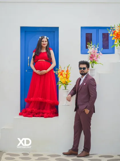 A classic, stylish portrait of a couple on a white staircase set, perfect for a modern maternity shoot.