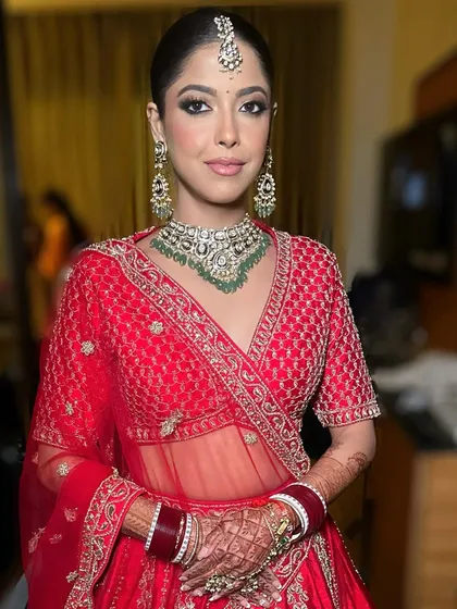 The complete look, with the bride looking radiant and confident. The dewy makeup provides a perfect balance to the rich red of her lehenga and the sparkle of her jewelry.
