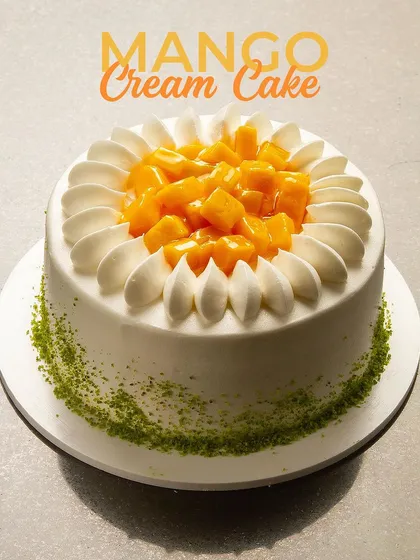 A celebration of seasonal flavour, this is my Mango Cream Cake. It's topped with a generous amount of fresh, diced mango and surrounded by delicate swirls of light cream, with a sprinkle of green pistachio dust at the base.