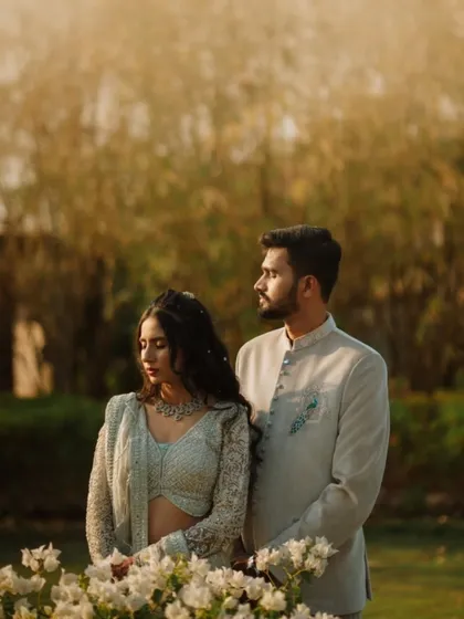 A serene portrait of the couple amidst white flowers and soft, golden light. Their calm expressions and coordinated outfits give this image a peaceful and sophisticated quality.