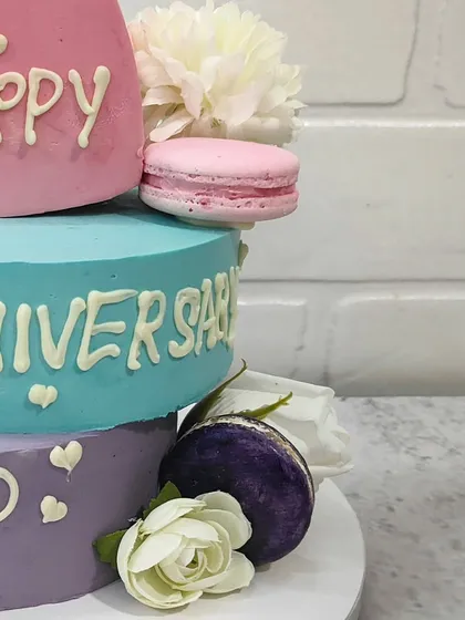 A closer view of the anniversary cake, showing the delicate fresh flowers and macarons that add a touch of elegance and flavor.