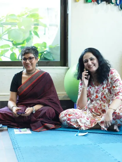 A moment of connection and a smile, as one woman takes a call while another listens to the group.