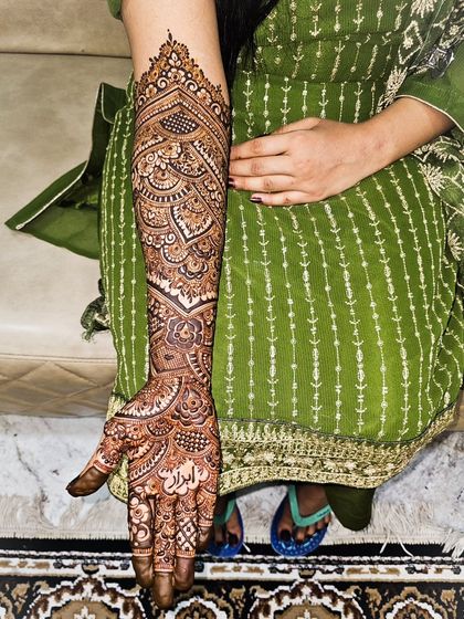 A full arm of intricate bridal henna, featuring a personalized name in Arabic script.