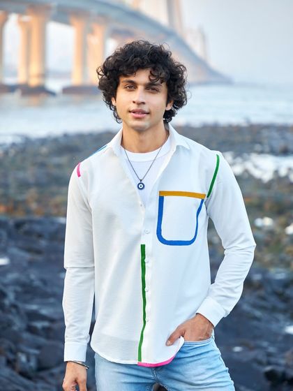Beat the monsoon blues with a special shopping spree. This white shirt with colorful piping is a perfect example of a garment that blends comfort and sophistication.