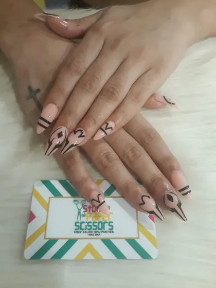 A very graphic and edgy design with sharp, abstract black line work on a nude base. This custom art on stiletto extensions is for someone who wants a truly unique look.