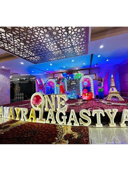A wide shot of the Cocomelon stage for 'AMAYRA & AGASTYA', showcasing the full setup with multiple themed backdrops and props.