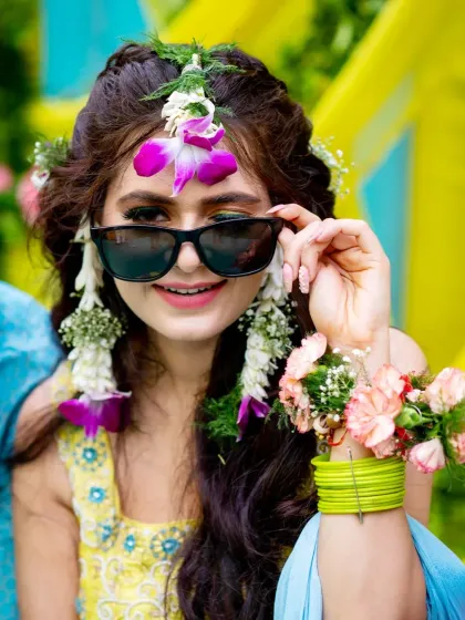 The fun and playful side of a haldi ceremony. This bride, with her floral jewelry and cool shades, perfectly embodies the vibrant and joyful spirit of pre-wedding celebrations.