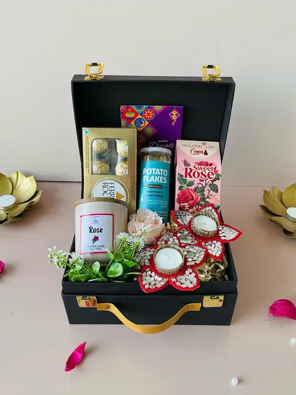 This black suitcase box is filled with a rose-scented candle, Ferrero Rocher chocolates, and festive mirror-work T-light holders. It's a perfect blend of fragrance, flavor, and decor.