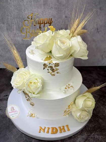 This elegant two-tier cake in pure white is adorned with fresh white roses, delicate wheat stalks, and gold leaf accents. It’s a timeless design perfect for a sophisticated 45th birthday celebration.