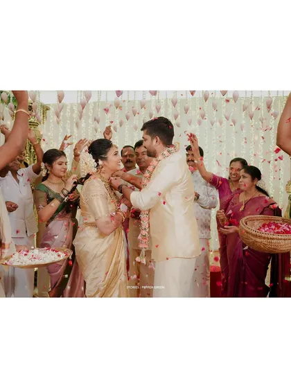The moment of the garland exchange, captured amidst a shower of flower petals and the smiles of their loved ones.