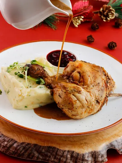 A classic Christmas dish of roasted chicken leg with mashed potatoes and cranberry sauce.
