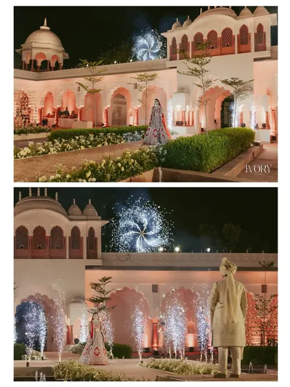 The bride's solitary walk towards the Varmala stage, set against the magnificent architecture and dazzling fireworks, creates a powerful and regal portrait.