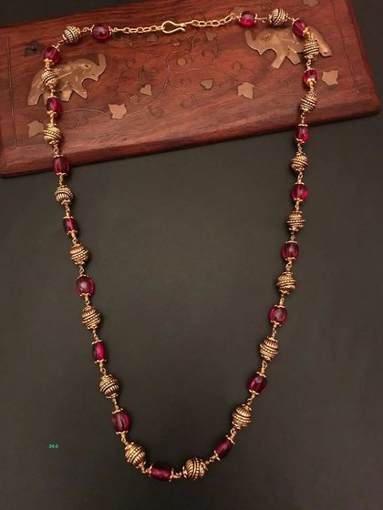 This 92.5 silver gold-plated necklace features beautiful ruby-colored beads and ornate golden beads. It's a vibrant and elegant piece for your collection.