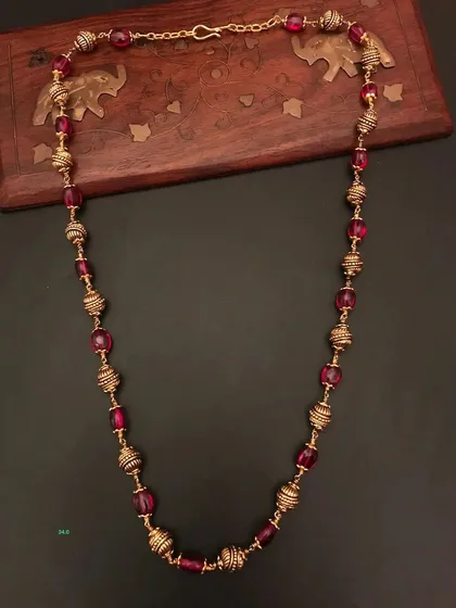 This 92.5 silver gold-plated necklace features beautiful ruby-colored beads and ornate golden beads. It's a vibrant and elegant piece for your collection.