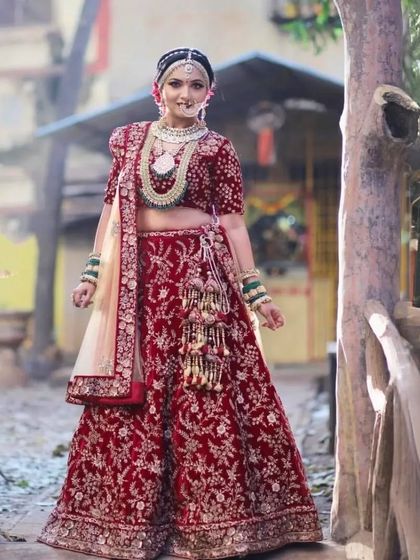 This bride looks absolutely majestic in a deep red velvet lehenga. The full set of jewellery, including the heavy necklace and nath, completes her royal look.