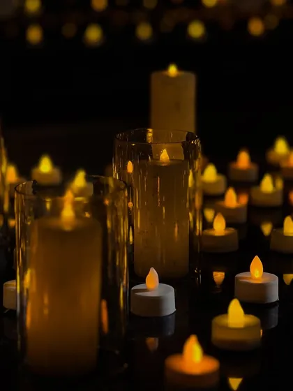 A close-up of the candlelit decor that defines my enchanted themes. A sea of LED candles and tea lights creates a safe yet magical flickering glow, reflecting beautifully on the dark surfaces.