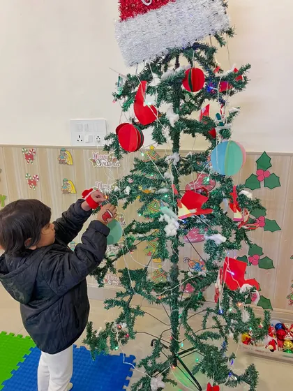 A young boy adds his own handmade ornament to the Christmas tree.