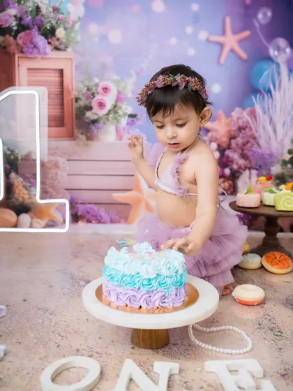 A moment of concentration amidst the fun. This little one is carefully inspecting her first birthday cake before diving back in.