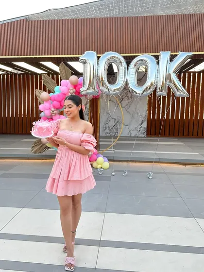 A proud moment for the creator, holding a custom cake in front of the festive backdrop we designed to celebrate her achievement.
