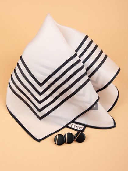 A creative fold of the black and white striped pocket square, styled with matching buttons.