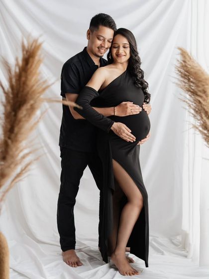 A full-length portrait showing their connection. The way he holds her close, both with their hands on the baby bump, makes for such a loving and protective pose. The all-black attire gives the studio shot a timeless feel.