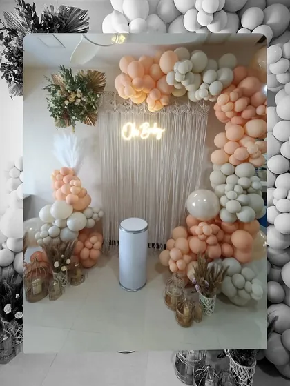 A chic and modern boho-themed baby shower. This setup uses macrame curtains, pampas grass, and a mix of peach and sage green balloons for a trendy, relaxed vibe.