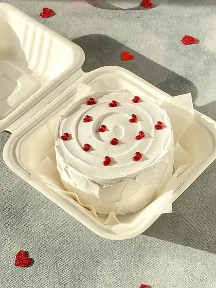 A Valentine's special Red Velvet bento cake. The simple white frosting is decorated with tiny red hearts for a classic, romantic look.