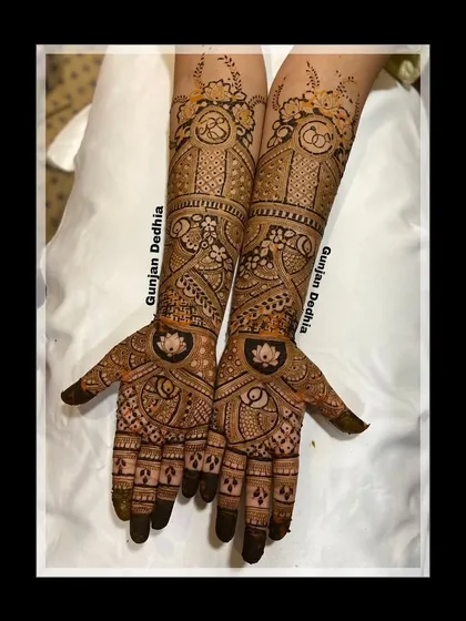 A beautiful engagement mehendi with lotus motifs on the palm and intricate bands on the arms. The design is both traditional and elegant.