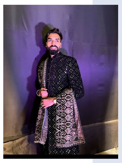 A close-up of our client in the black embroidered sherwani. The lighting highlights the beautiful texture and pattern of the fabric.