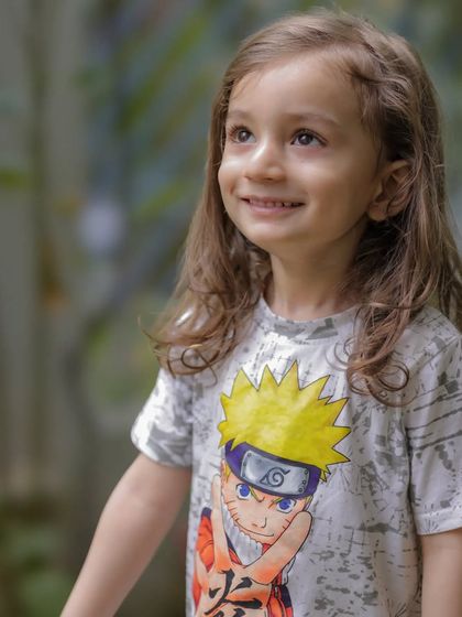 A beautiful candid portrait of a young girl looking up with a gentle smile. The natural outdoor lighting and her genuine expression make this a truly special moment.