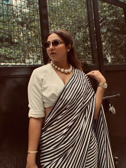 A close-up on the details: a classic pearl choker, rolled-up sleeves on the shirt-blouse, and retro sunglasses. It's these finishing touches that bring the whole look together.