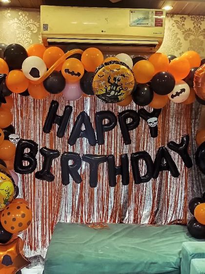 A fun Halloween-themed birthday decoration at home. An orange and black balloon arch with spooky foil balloons creates a unique party vibe.
