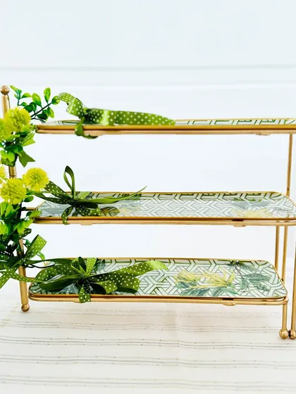 This close-up of the Bornea 3-tier stand highlights the beautiful botanical print on the trays and the elegant gold-finish frame, a perfect harmony of form and function.