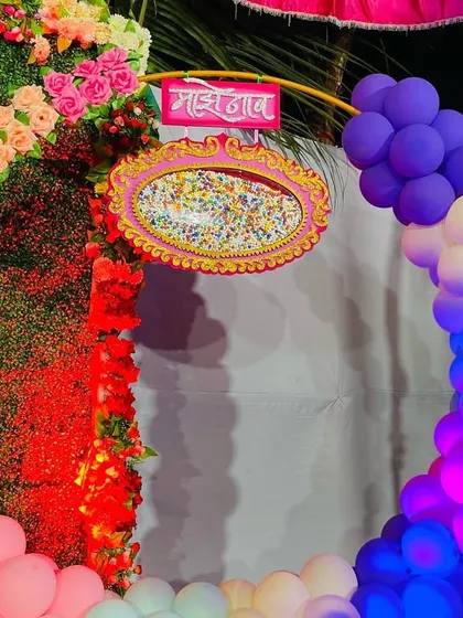 A close-up of a naming ceremony detail, showing a traditional 'madhli' plate next to a balloon arch.