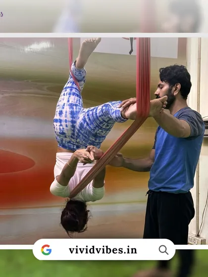 You can dream of flying, and we can help make it happen. An instructor assists a student in a supported inversion, a foundational pose for building confidence.