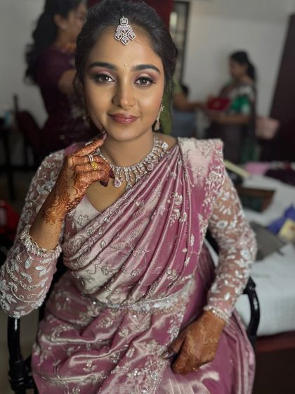 A smiling portrait of Surya, looking happy and confident in her reception makeover. The glam makeup perfectly suits her festive pink saree.