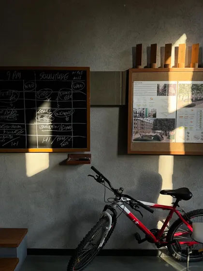 The warm evening light fills the studio, highlighting the contrast between the raw concrete walls and the organized chaos of our work. The bicycle leaning against the wall is a part of our daily studio life.