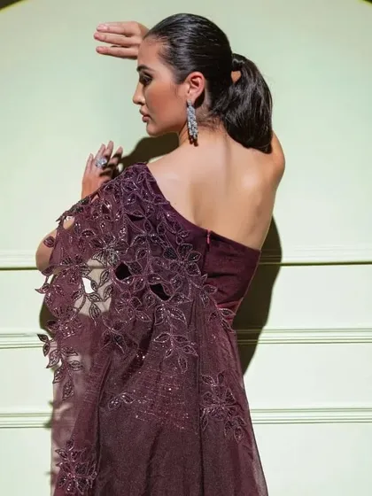 A model showcases a one-shoulder gown from "The Spotlight" collection, featuring a beautiful laser-cut and embroidered sleeve.
