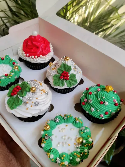 Getting into the festive spirit with this box of Christmas-themed cupcakes. Each one is decorated by hand with holiday designs like wreaths, Santa hats, and Christmas trees, all sparkling with edible glitter.
