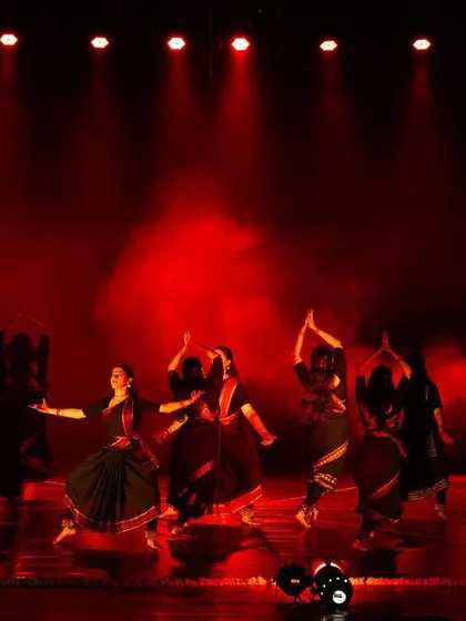 A large group of dancers on a dramatically lit stage during 'PADAM'. This shot captures the scale of a full company production and the power of a large ensemble.