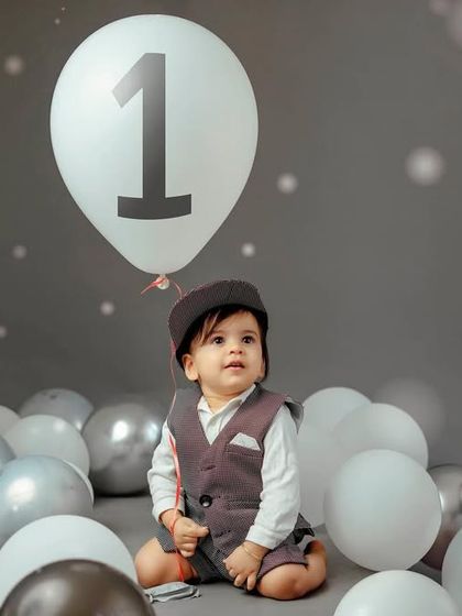 A moment of wonder. The monochrome balloons and simple background create a sophisticated look for a first birthday photoshoot.