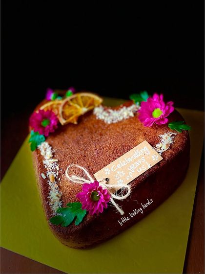 Another view of the heart-shaped orange gulkand nuts cake, showing the delicate decorations and custom tag.