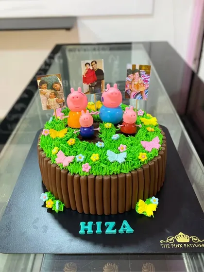 A lovely Peppa Pig garden cake. This design features a chocolate stick fence, green grass icing, and the Peppa Pig family enjoying a day out with photo memories.
