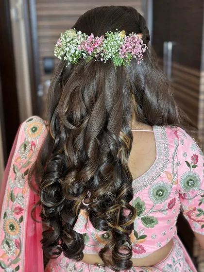 A fresh and youthful hairstyle for a Mayera or Mehendi look, featuring a crown of baby's breath and soft curls.