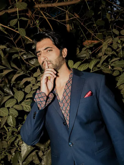 An outdoor, night-time portrait of actor Akshay Oberoi. The flash against the dark foliage creates a moody and mysterious atmosphere.