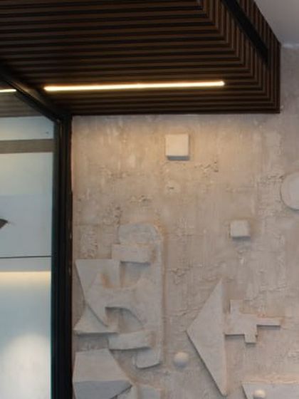 A detail shot of the abstract, geometric forms on our custom-designed concrete art wall. The play of light and shadow highlights the texture and depth of the piece.