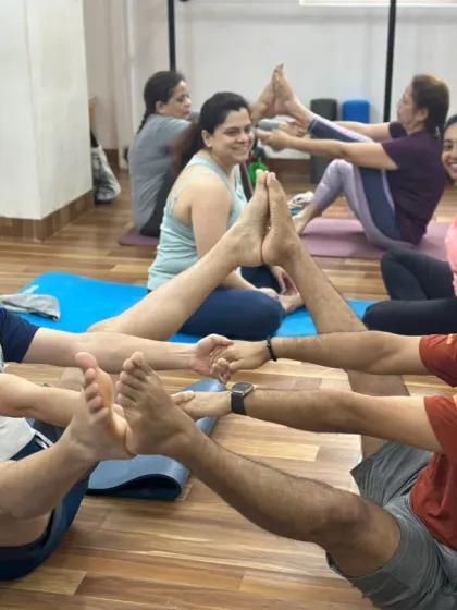A group of students enjoying a multi-person partner boat pose, creating a chain of trust and shared effort.