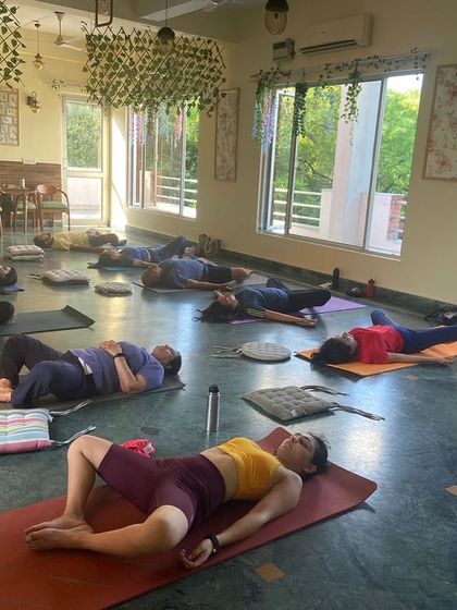 Students resting in Supta Baddha Konasana, or reclining bound angle pose, a restorative hip opener.